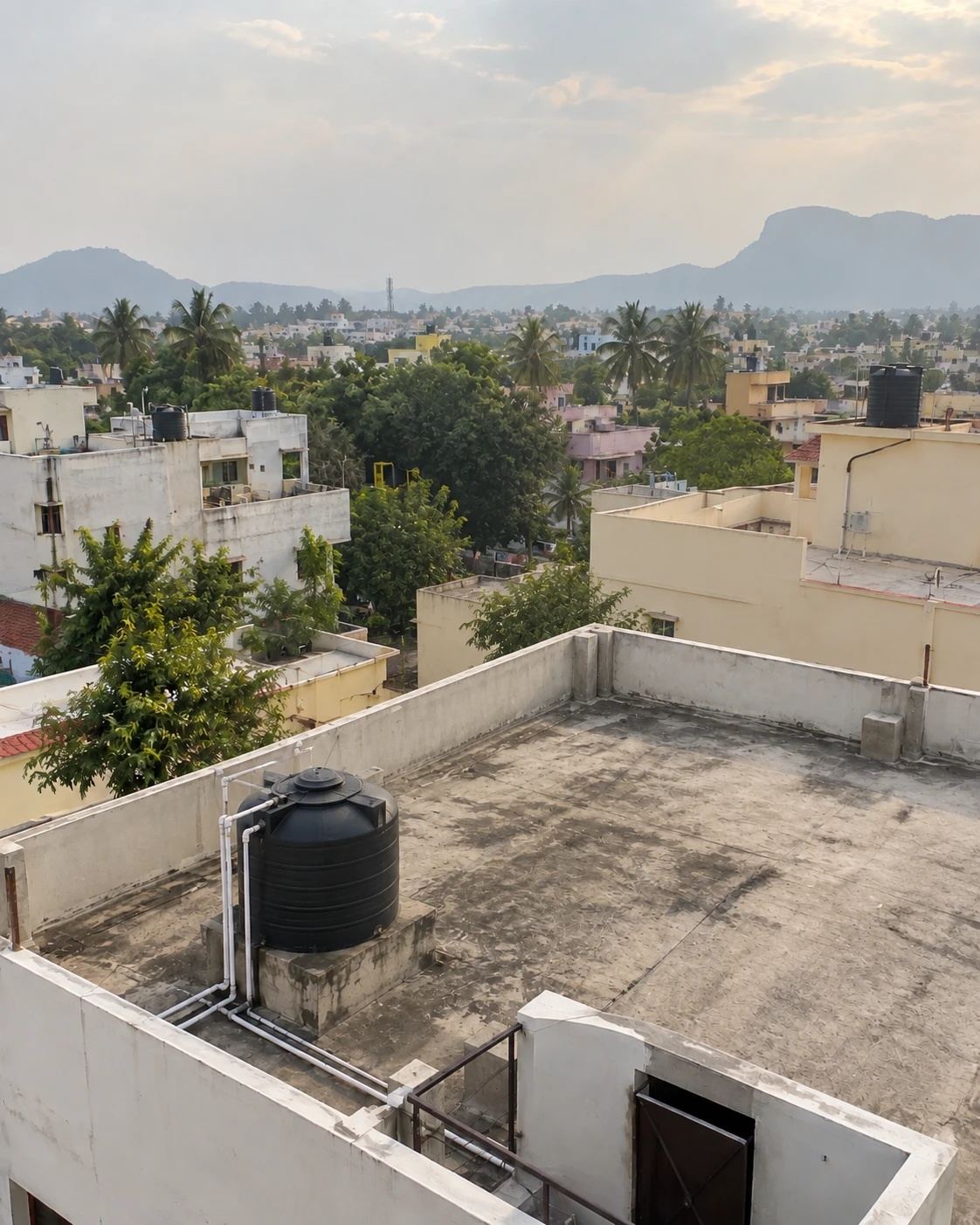 An empty concrete rooftop terrace with only a water tank, before solar installation